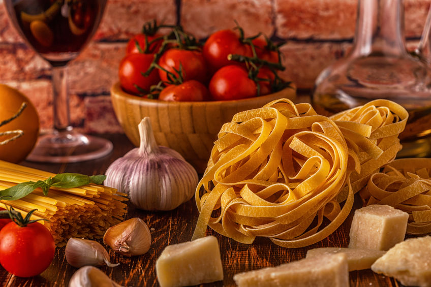 Products for cooking - pasta, tomatoes, garlic, olive oil and red wine. Selective focus.